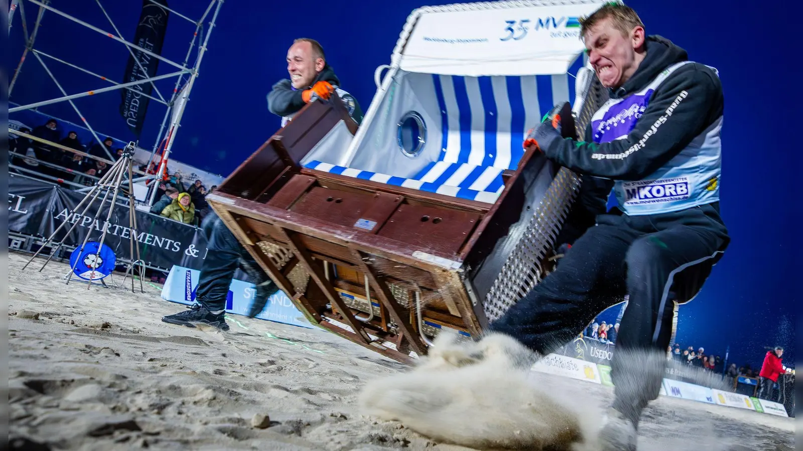 Sie geben alles: Das Team „Quad Safari Usedom“ mit Phillip Schmidt (l) und Finley Liemen (r) gewinnt den Finallauf bei der 18. Strandkorb Weltmeisterschaft auf der Insel Usedom mit einer neuen Weltrekordzeit von 4,56 Sekunden. Die Zweierteams müssen bei dem Wettkampf einen etwa 60 Kilogramm schweren Strandkorb über die 20 Meter lange Strecke über den Ostseestrand ins Ziel schleppen. (Foto: Jens Büttner/dpa)
