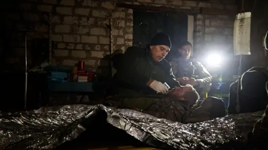 Ein Mann gibt einem verwundeten ukrainischen Soldaten in einem Unterstand in Donezk etwas zu trinken. (Foto: Roman Chop/AP/dpa)