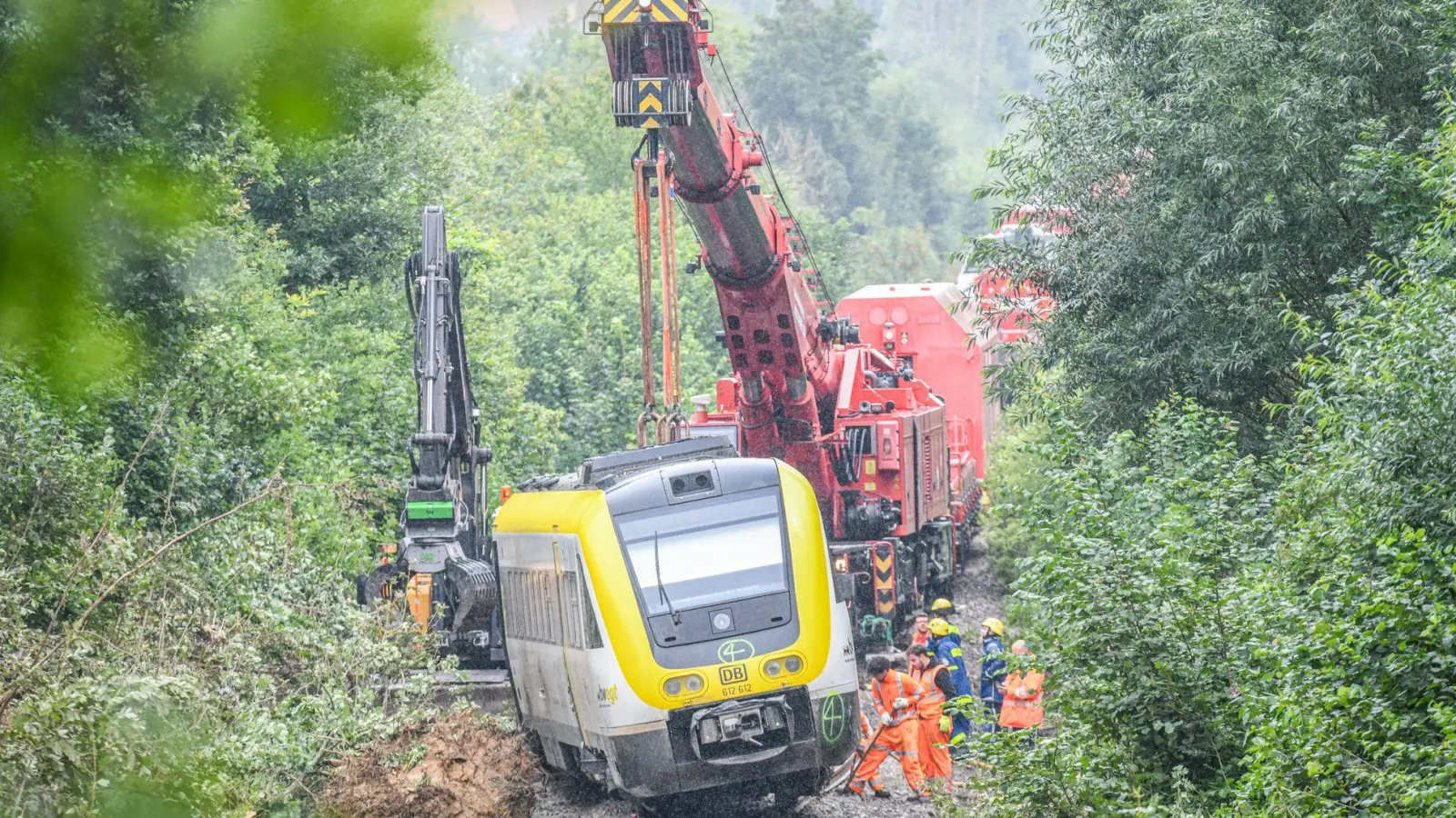 Mit einem Kran wird an der Unfallstelle, an der ein Regionalzug entgleist ist, gearbeitet. Ein Regionalexpress war am Sonntagabend (27.07.2025) in Riedlingen nach bisherigen Erkenntnissen infolge eines Hangrutsches entgleist. (Foto: Jason Tschepljakow/dpa)