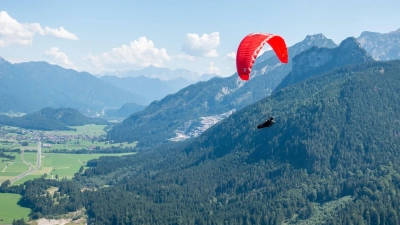 Verkehr am Himmel über Pfronten: Ein Solo-Paraglider fliegt neben dem Autoren und seinem Tandempiloten in Richtung Tal. (Foto: Andreas Drouve/dpa-tmn)