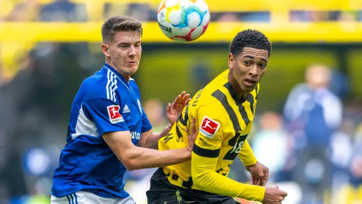 Schalkes Florian Flick (l) und Dortmunds Jude Bellingham kämpfen um den Ball. (Foto: David Inderlied/dpa/Archivbild)