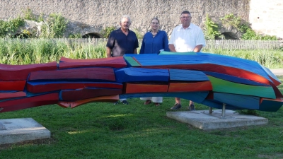 Die Skulptur „Brückenbogen“ erstrahlt wieder in kräftigen Farben. Darüber freuen sich (v.l.) Zweiter Bürgermeister Herbert Argmann, Künstlerin Cornelia Königsperger und Heimatvereins-Vorsitzender Hans Popp. (Foto: Daniel Ammon)