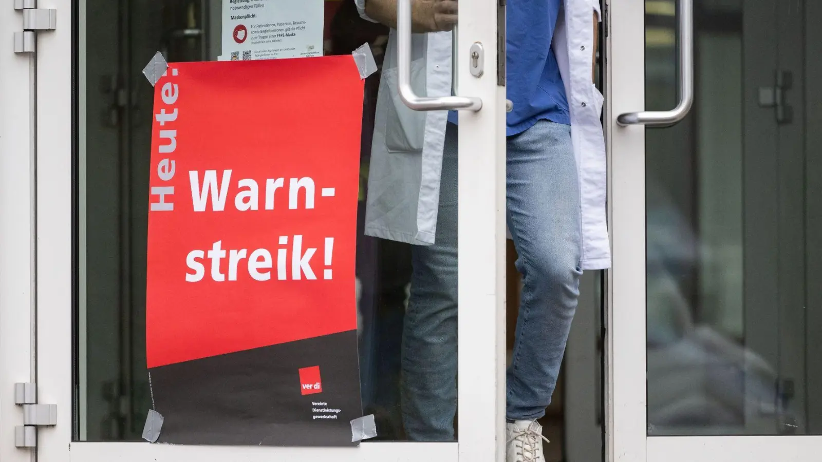 Ein Plakat mit der Aufschrift „Heute Warnstreik“ hängt am Eingang eines Gebäudes. (Foto: Marijan Murat/dpa)