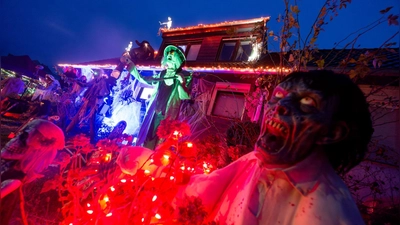 Gruselige Figuren stehen in Mettmann vor einem beleuchteten Halloween-Haus. (Foto: Henning Kaiser/dpa)