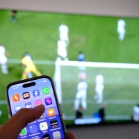 Nebenbei mal daddeln: Während das Fußballspiel läuft, schauen viele Zuschauer nebenbei aufs Handy. (Symbolbild) (Foto: Bernd Weißbrod/dpa)