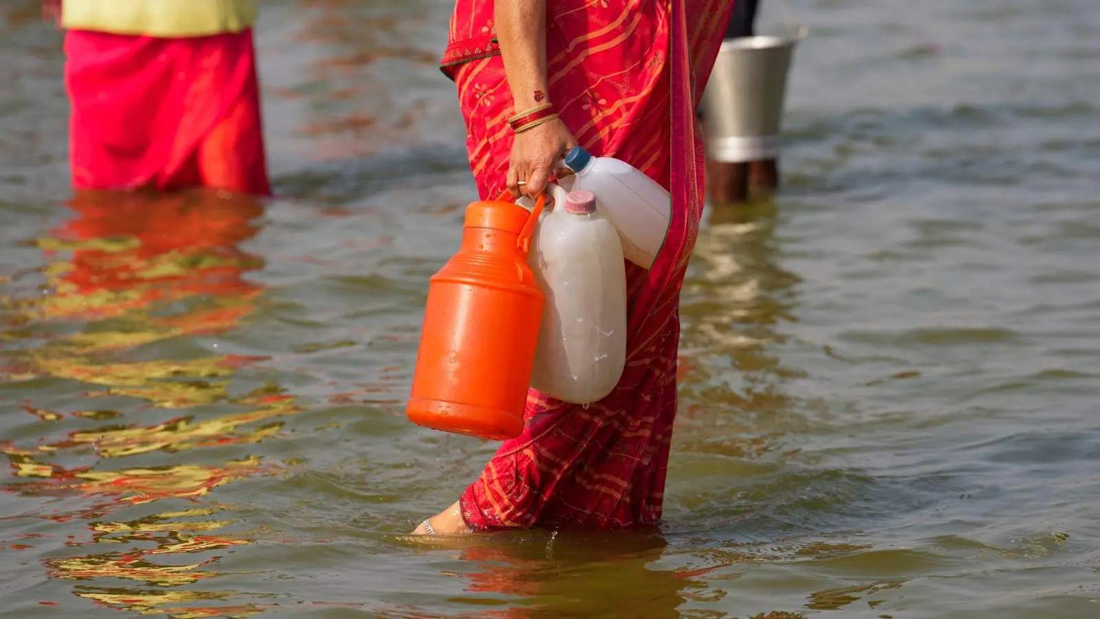 Eine Hinduistin geht nach dem Wasserholen mit Kunststoffkanistern im Sangam, dem Zusammenfluss des Ganges und Yamuna. (Foto: Rajesh Kumar Singh/AP)