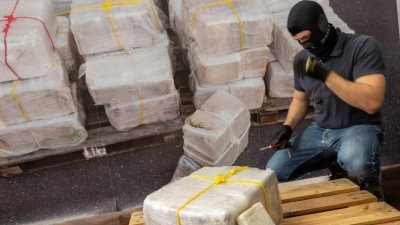 Ein Zollbeamter kniet vor einem Teil der zur bislang größten Einzelsicherstellung von Kokain in Bayern. (Foto: Peter Kneffel/dpa)