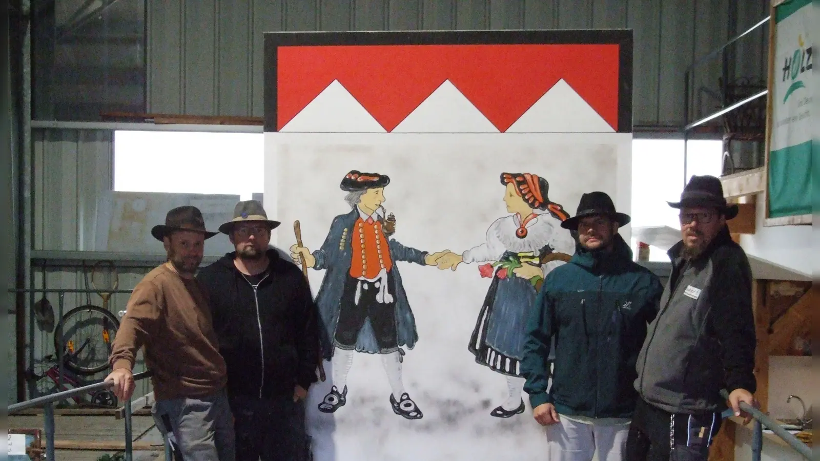 Mit Rainer Geymann, Jörg Heßler (von links) und Christian Fincke (rechts) montiert ein routiniertes Team des städtischen Bauhofs die Motivkulissen auf die Mooswiesen-Festwagen. Nicolaj Vorholzer (2. von rechts) schaute sich den Wagen an, auf dem am Sonntag die Fränkische Hochzeit zu sehen ist. (Foto: Jasmin Kiendl  )