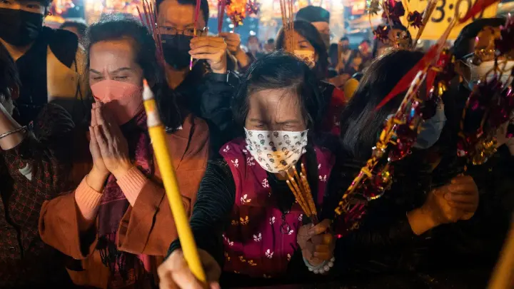 Gläubige mit Mund-Nasen-Schutz verbrennen ihre ersten Räucherstäbchen, während sie im Wong-Tai-Sin-Tempel das Neujahrsfest in Hongkong feiern. (Foto: Bertha Wang/AP/dpa)