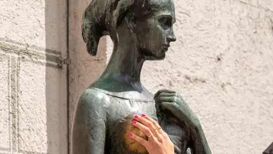 Eine Frau greift dem Bronzedenkmal Julia am Alten Rathaus an die Brust. (Foto: Peter Kneffel/dpa/Archivbild)