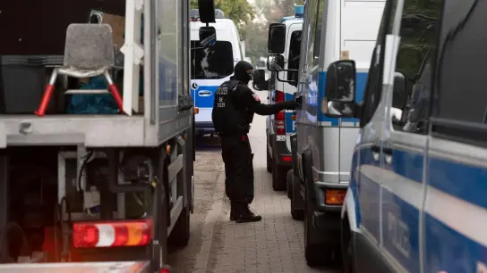 Ein Polizeibeamter steht zwischen Einsatzfahrzeugen am Vereinsheim der Rockergruppe &quot;Hells Angels MC Berlin Central&quot; in Berlin. (Foto: Paul Zinken/dpa)