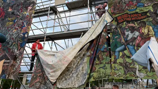 Documenta-Mitarbeiter bauen das umstrittene Großbanner &quot;People&#39;s Justice&quot; des indonesischen Künstlerkollektivs Taring Padi auf dem Friedrichsplatz ab. (Foto: Uwe Zucchi/dpa)