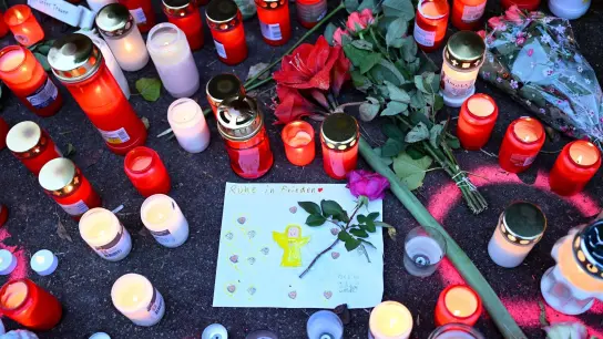 Kerzen und Blumen stehen an einem Tatort. (Foto: Bernd Weißbrod/dpa)