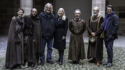 Mitglieder des Casts von „The Uprising” zeigen sich im Innenhof des Pellerhauses in Nürnberg im Kostüm (v.l.): Thomasin McKenzie, Jamie Bell, Regisseur Paul Greengrass, Judith Erber (FFF Bayern), Tom Hollander, Mark Redhead sowie Philipp Kreuzer (Produzent, Supernix). (Foto: Betina la Plante/FFF Bayern)