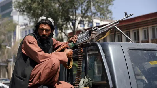Ein Taliban-Kämpfer sitzt in Kabul mit einem Maschinengewehr auf der Ladefläche eines Fahrzeugs. (Foto: -/AP/dpa)