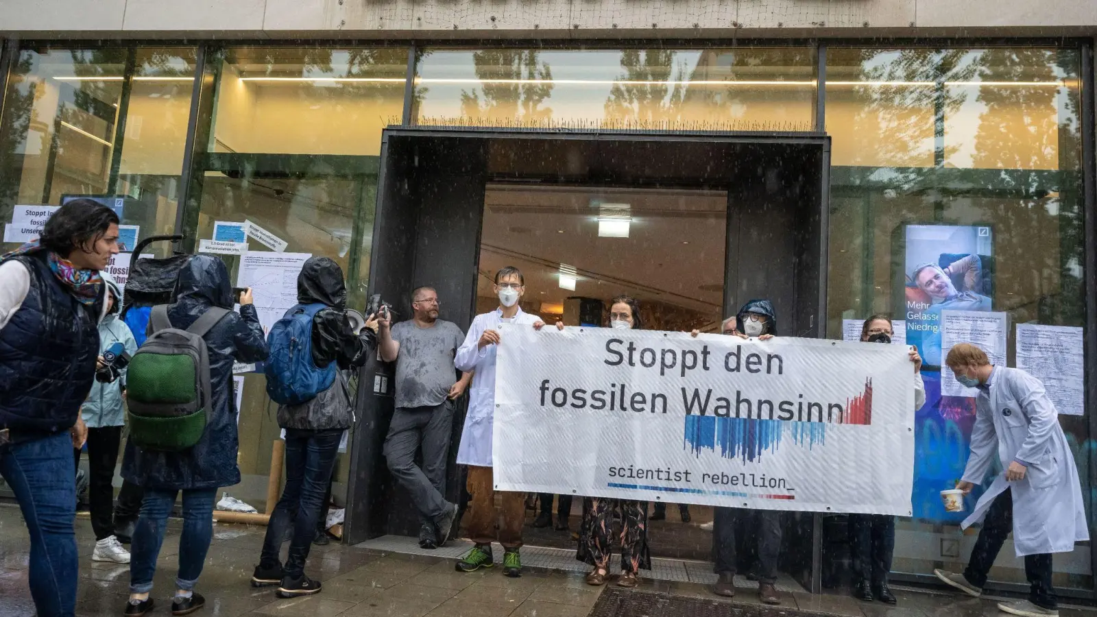 Aktivisten nehmen vor und in einer Filiale der Deutschen Bank in der bayerischen Landeshauptstadt an einer Protestaktion der „Scientist Rebellion Deutschland“ teil. (Foto: Peter Kneffel/dpa)