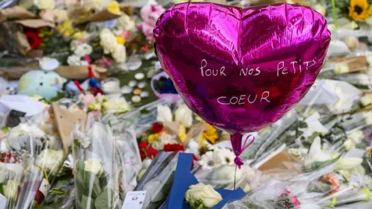 Mit Blumen und Luftballons gedenken die Menschen in der französischen Alpenstadt Annecy der Opfer eines Messerangriffs auf einem Kinderspielplatz. Das Motiv des Täters ist weiterhin unbekannt. (Foto: Jean-Christophe Bott/KEYSTONE/dpa)