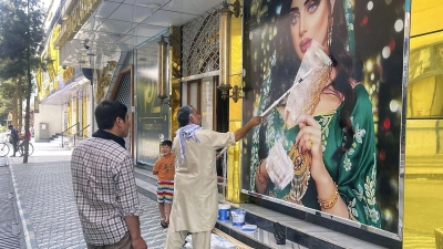 Ein Mitarbeiter eines Schönheitssalons übermalt im August 2021 ein großes Foto einer Frau, nachdem die Taliban in die afghanische Hauptstadt eingedrungen sind. (Foto: -/Kyodo/dpa)