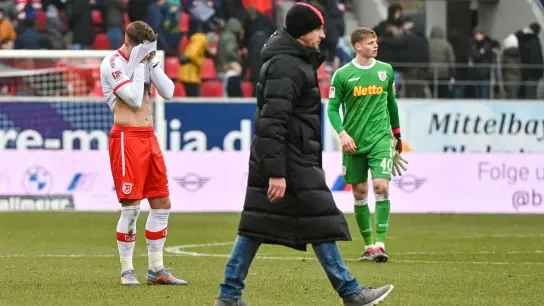 Die Mannschaft von Regensburg steht nach dem verlorenen Spiel gegen Düsseldorf enttäuscht auf dem Rasen. (Foto: Armin Weigel/dpa)
