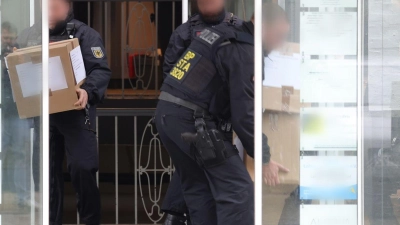 Polizeibeamte tragen in Kartons sichergestelltes Material aus einem Gebäude. (Foto: Gianni Gattus/dpa)