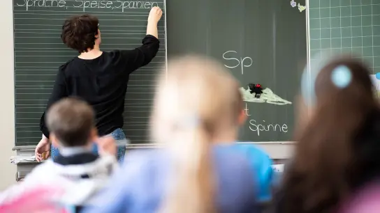 Eine Lehrerin schreibt in einer Grundschule Wörter an eine Tafel. (Foto: Sebastian Gollnow/dpa/Illustration)