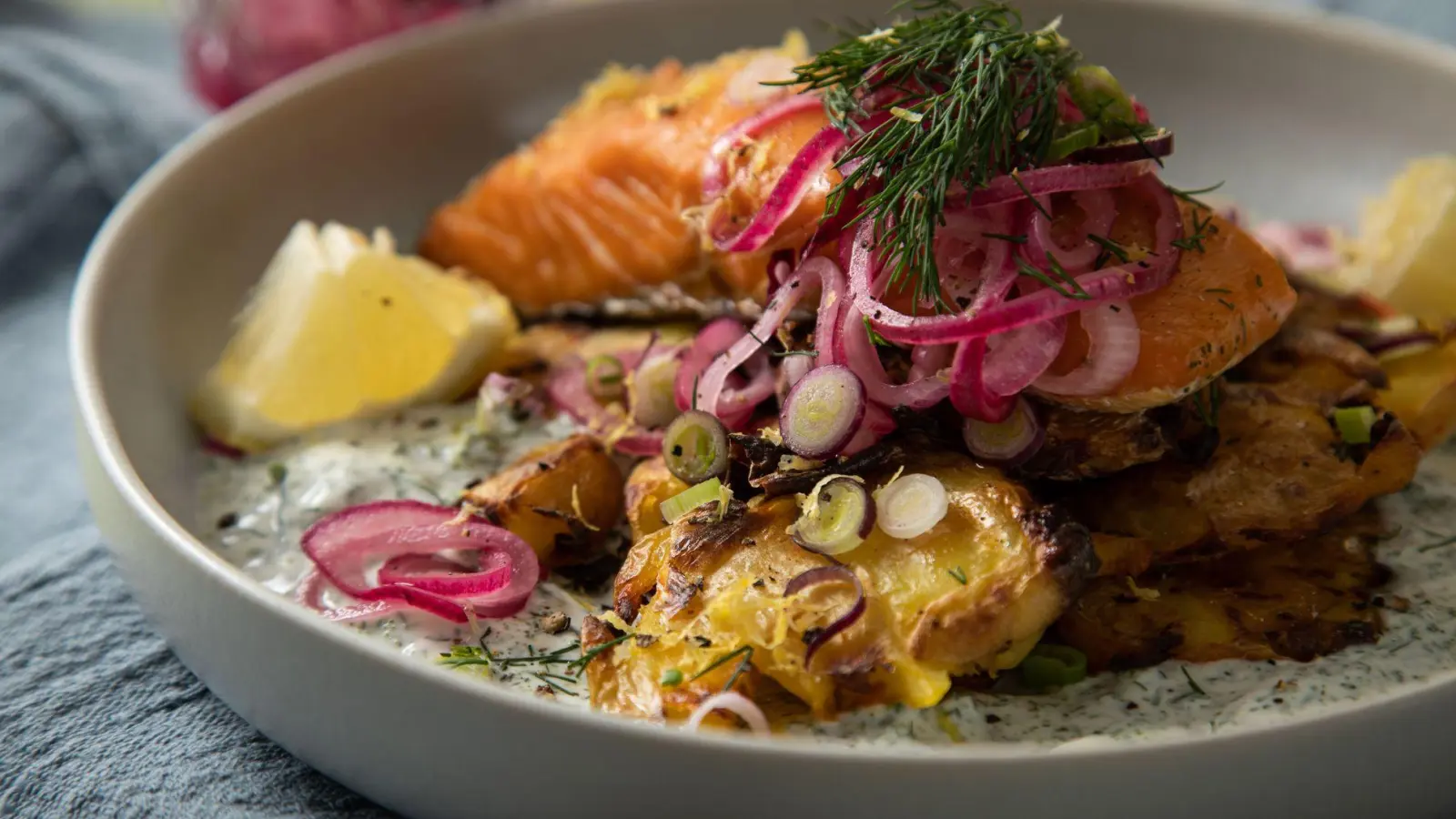 Eingelegte rote Zwiebeln toppen den Schweden-Salat mit crispy smashed Potatoes und Lachs. (Foto: Christin Klose/dpa-tmn)