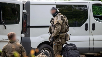 Beamte eines Spezialeinsatzkommandos (SEK) stehen neben einem Transporter: Zwei Wochen nach dem tödlichen Schuss bei der Kirmes in Lüdenscheid hat die Polizei eine Wohnung durchsucht und eine Person vorläufig festgenommen. (Foto: Markus Klümper/dpa)