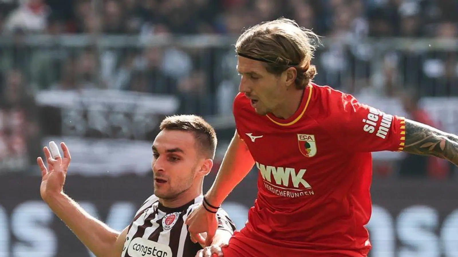 Im Zweikampf: Kristijan Jakić vom FC Augsburg (r) und St. Paulis James Sands. (Foto: Christian Charisius/dpa)