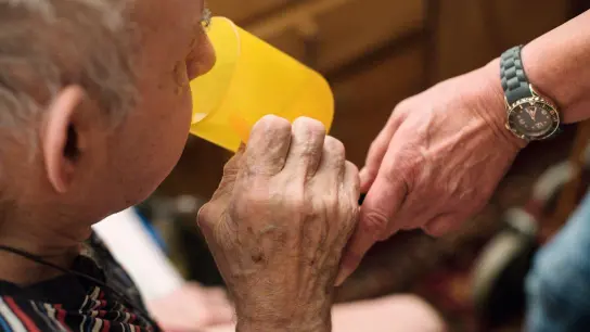 Eine ambulante Pflegerin hilft einem alten Mann bei der Tabletteneinnahme. (Foto: Jana Bauch/dpa)