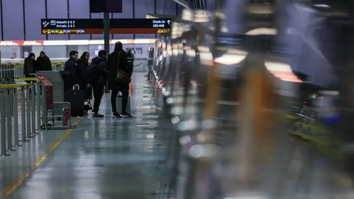 Reisende stehen am Flughafen Köln/Bonn vor einem Schalter. (Foto: Oliver Berg/dpa)