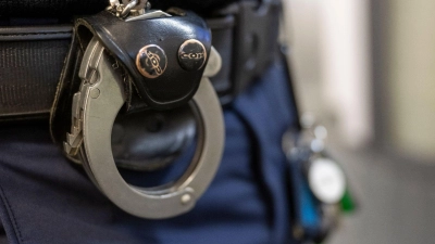 Eine Handschelle hängt am Gürtel eines Polizisten der Polizeiinspektion 11. (Foto: Peter Kneffel/dpa)
