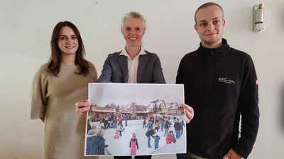 Daniela Übler, Birgit Grübler und Jochen Schauer (von links) zeigen ein Foto der Schlittschuhbahn. Diese wird beim Weihnachtsmarkt heuer erstmals am Bad Windsheimer Marktplatz stehen. (Foto: Katrin Merklein)