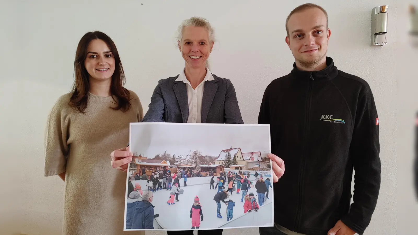 Daniela Übler, Birgit Grübler und Jochen Schauer (von links) zeigen ein Foto der Schlittschuhbahn. Diese wird beim Weihnachtsmarkt heuer erstmals am Bad Windsheimer Marktplatz stehen. (Foto: Katrin Merklein)