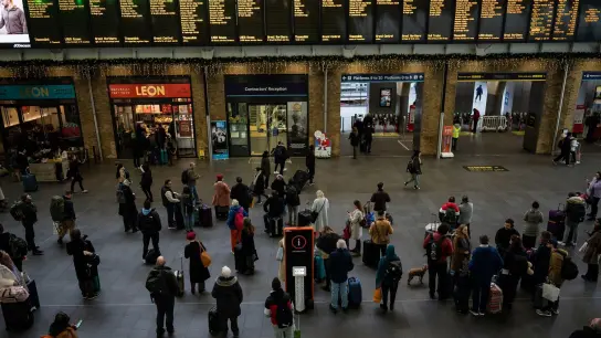 Menschen stehen an Anzeigetafeln im Bahnhof Kings Cross in London. Streiks behindern den Reiseverkehr zu Weihnachten erheblich. (Foto: Aaron Chown/PA/dpa)