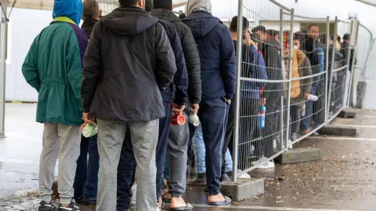 In der Landeserstaufnahmestelle warten Flüchtlinge in einer Schlange vor der Essensausgabe. (Foto: Stefan Puchner/dpa/Archivbild)