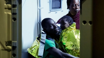 Gerettete Migranten gehen auf der italienischen Insel Lampedusa von einem Boot an Land. (Foto: Cecilia Fabiano/LaPresse via AP/dpa)