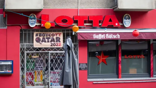 Die Kneipe Lotta in der Kölner Südstadt boykottiert die Fußball-WM-Spiele in Katar und hat über dem Eingang ein Banner aufgehängt. (Foto: Thomas Banneyer/dpa)