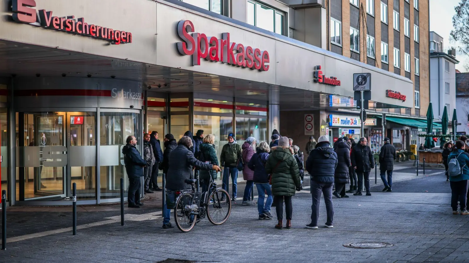Nach einem Einbruch in den Tresorraum einer Bankfiliale in Gelsenkirchen warten Menschen vor dem Eingang auf Informationen. (Foto: Christoph Reichwein/dpa)