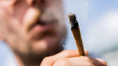 Ein Mann raucht bei der Auftaktkundgebung einer Demonstrationen für eine zügige Legalisierung von Cannabis, dem „Global Marijuana March 2022“, am Brandenburger Tor einen Joint mit Medizinalcannabis. (Foto: Christoph Soeder/dpa)