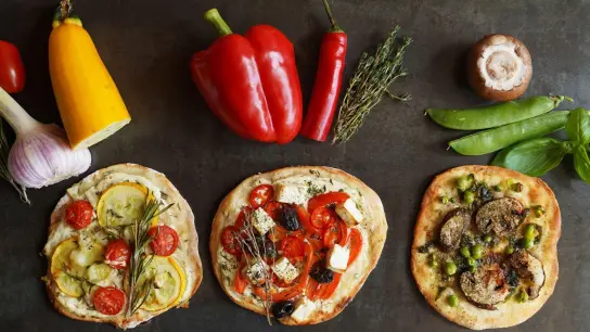 Gelbe Zucchini, rote Paprikaschoten oder grüne Erbsen - der Belag für die Mini-Pizzen erinnert an eine Ampel. (Foto: Manfred Zimmer/herrgruenkocht.de/dpa-tmn)