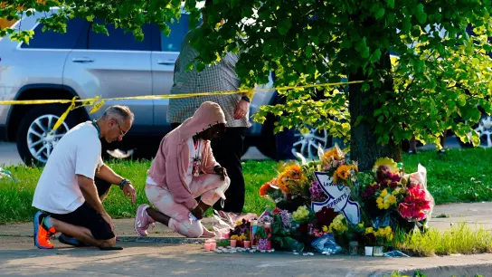 Menschen knien vor Blumen, um den Opfern tödlicher Schüsse in einem Supermarkt in Buffalo die letzte Ehre zu erweisen. (Foto: Matt Rourke/AP/dpa)