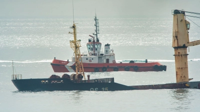 Ein Schlepper liegt hinter dem Frachter, der halb gesunken ist. (Foto: Marcos Moreno/AP/dpa)