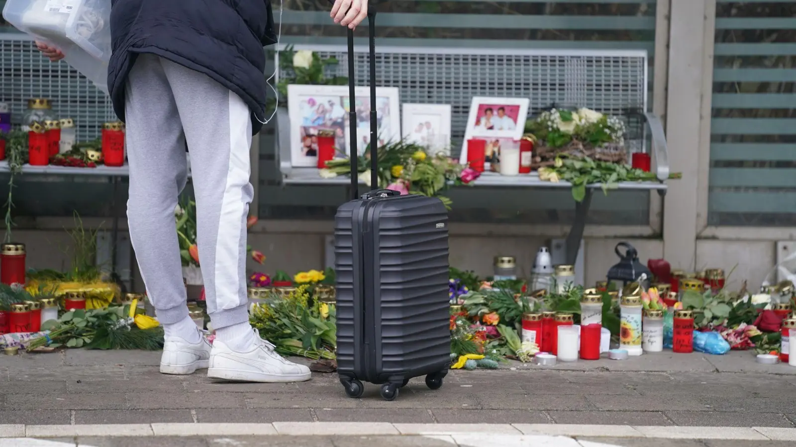 Eine Reisende schaut sich die Blumen, Kerzen und verschiedene Bilder im Wartehäuschen am Bahnhof zum Gedenken an die Opfer der Messerattacke an. (Foto: Marcus Brandt/dpa)