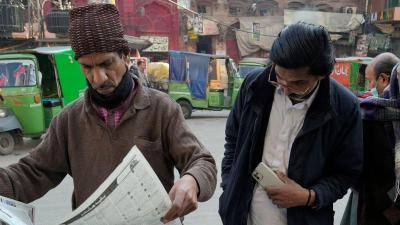 Menschen lesen an einem Stand in Lahore die Morgenzeitung. Pakistans Wahlen waren überschattet von Internetsperren und Manipulationsvorwürfen. (Foto: K.M. Chaudary/AP/dpa)