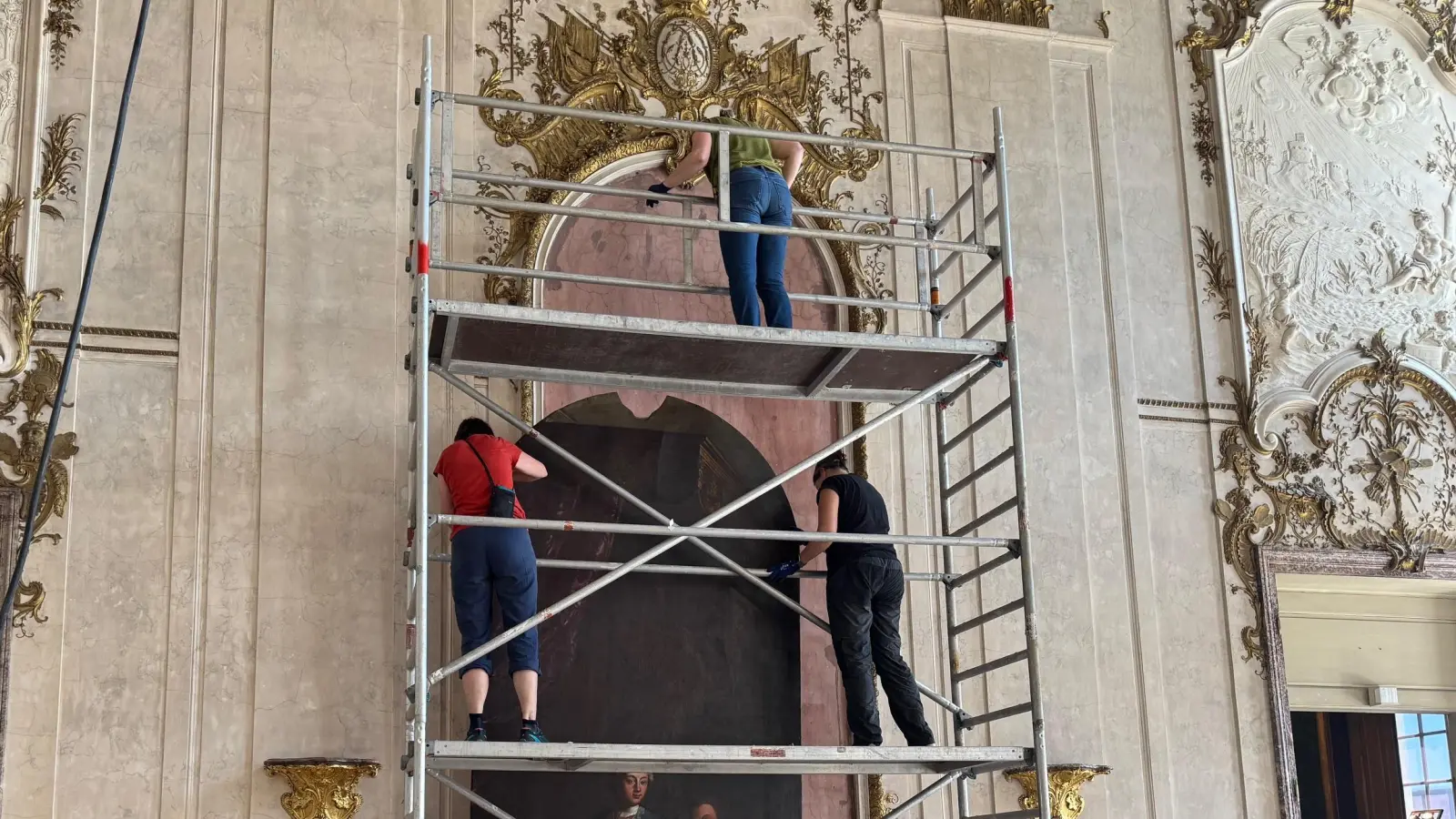 Das über vier Meter hohe Bildnis des Markgrafen Carl Wilhelm Friedrich wird nach oben gehievt, um es an seinem angestammten Platz im Festsaal des Schlosses zu befestigen. (Foto: Lara Hausleitner)