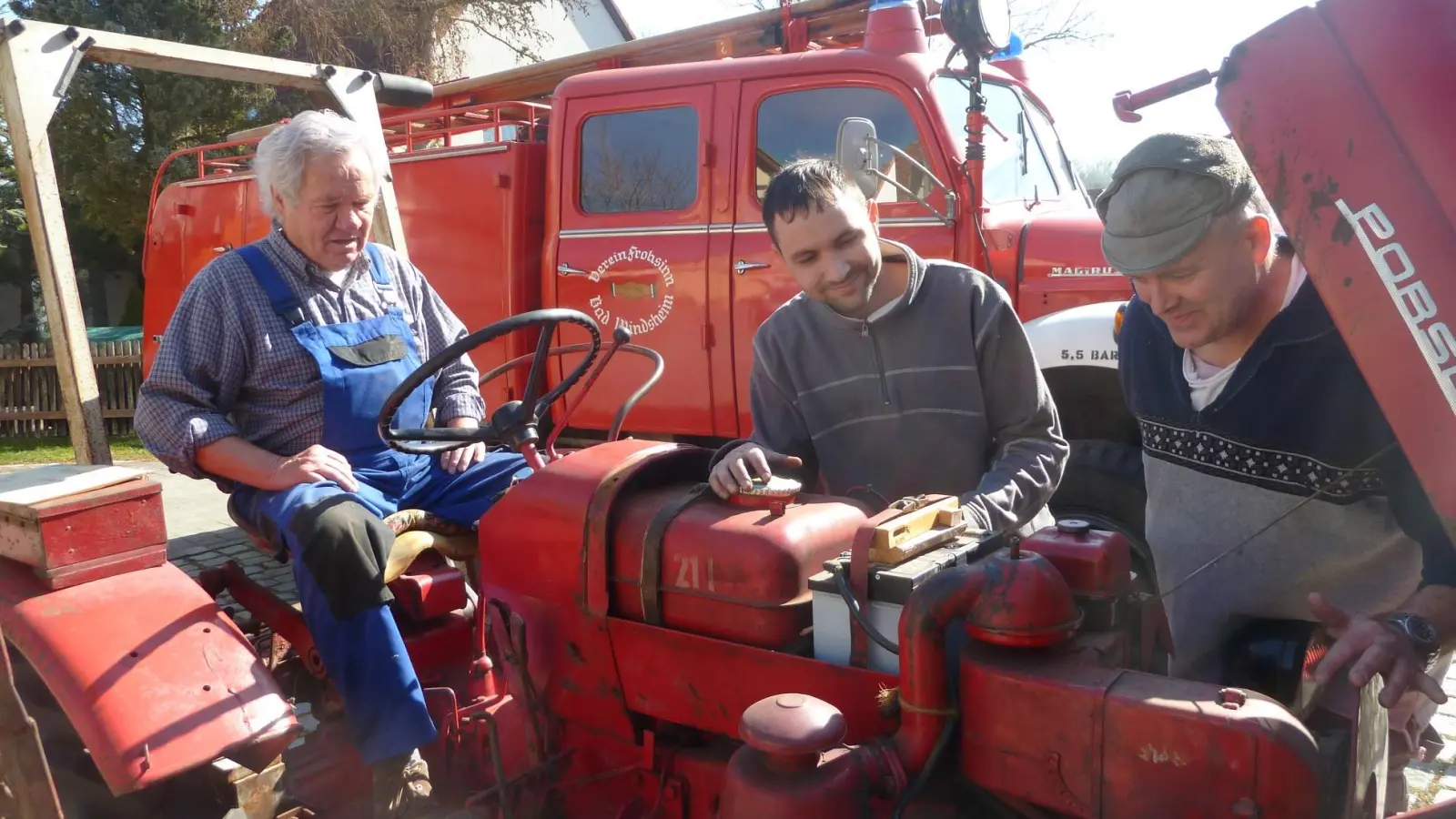Wolfgang Schmotzer (rechts) überprüft mit seinem Team einen alten Traktor. Im Hintergrund ist ein 65 Jahre altes, funktionsfähiges Feuerwehrauto zu sehen. (Foto: Ernst Werner Schneider)