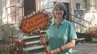 Heidi Beigel mit jenem Schild, das beim Sommerfest des Kindergartens bei einem großen Festzug zum Einsatz kam: 50 Jahre besteht der Kindergarten, seit 40 Jahren ist sie dabei. (Foto: Ulli Ganter)