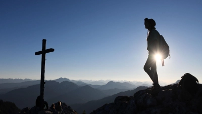 Eine Ausflüglerin genießt den Blick am Gipfelkreuz des Taubensteins. (Foto: Tobias Hase/dpa)