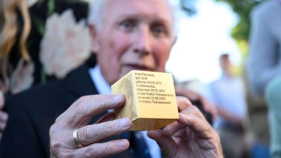 Der Münchner Toni Heilmaier, der zufällig entdeckte, dass seine Großmutter Anna Paroubek Holocaust-Opfer wurde, hält ein Erinnerungszeichen in den Händen. (Foto: Lukas Barth-Tuttas/dpa)