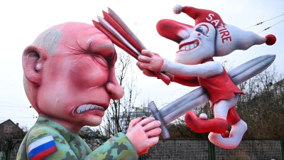 Ein Mottowagen auf dem Putin die Düsseldorfer Karnevalsfigur Hoppeditz aufspießt, fährt aus der Wagenbauhalle in Düsseldorf.  (Foto: Federico Gambarini/dpa)